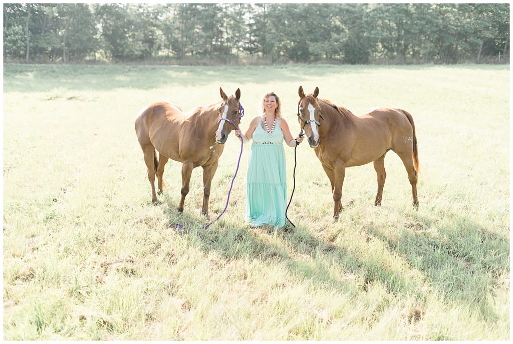 Woman posing in image with two horses