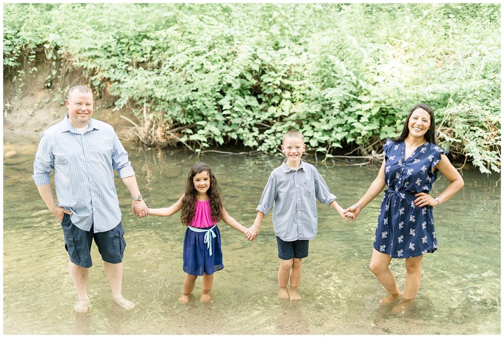 family standing in creek barefoot