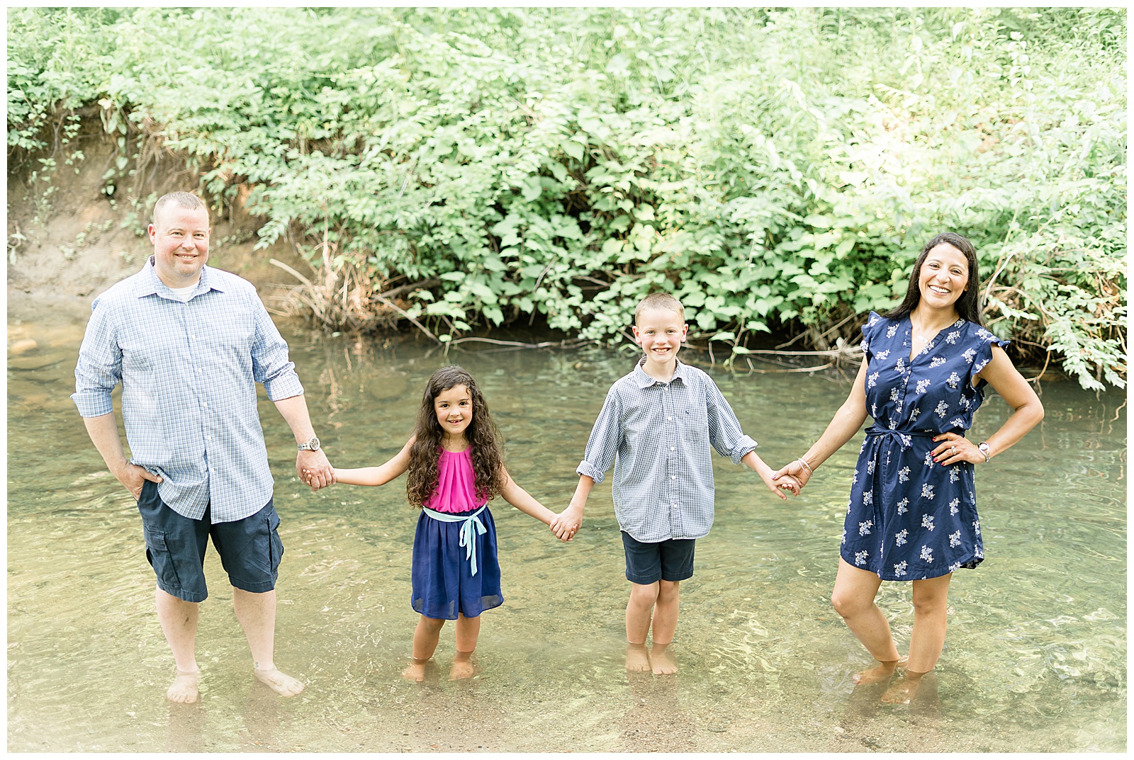 Family standing in river holding hands