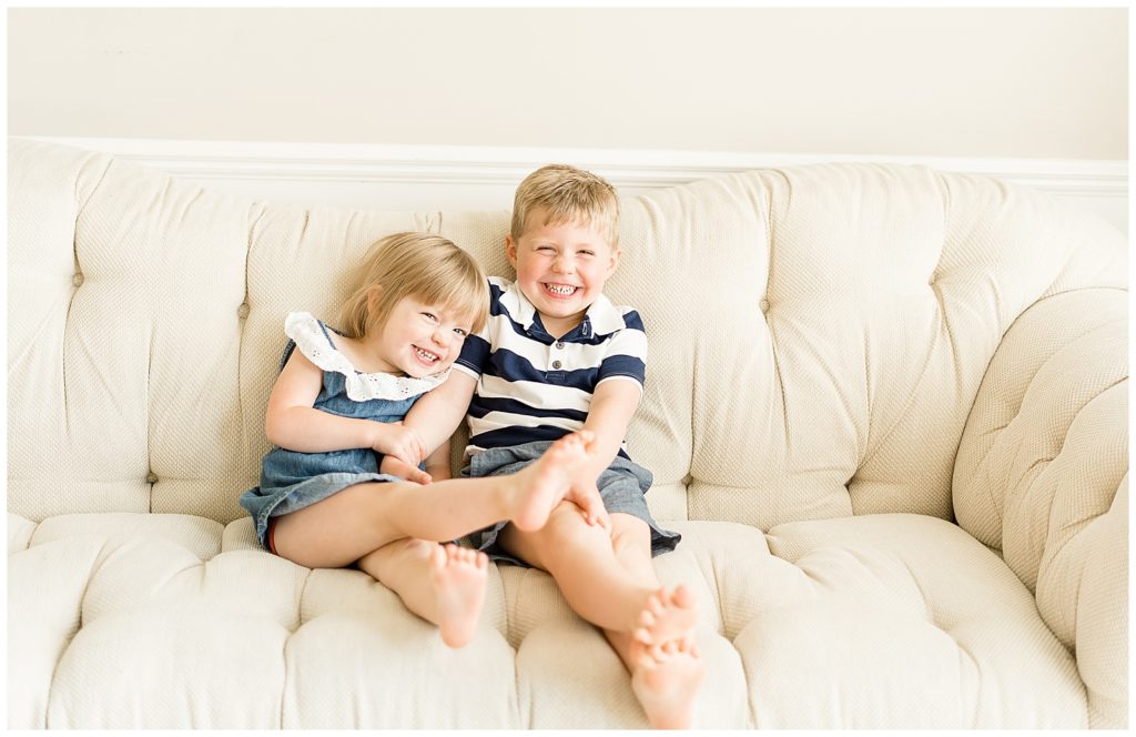 sister and brother smiling while on a couch