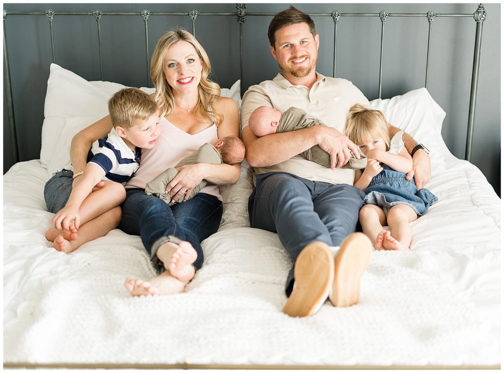 whole family smiling at camera holding newborn twin boys