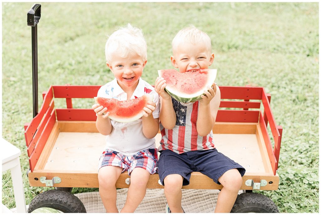 two little boys eating watermelon in a wagon