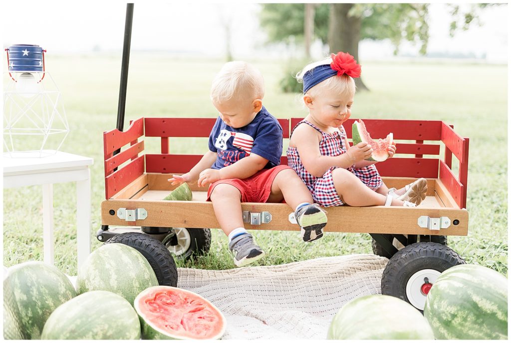 little boy and girl sitting on wagon eating watermelon
