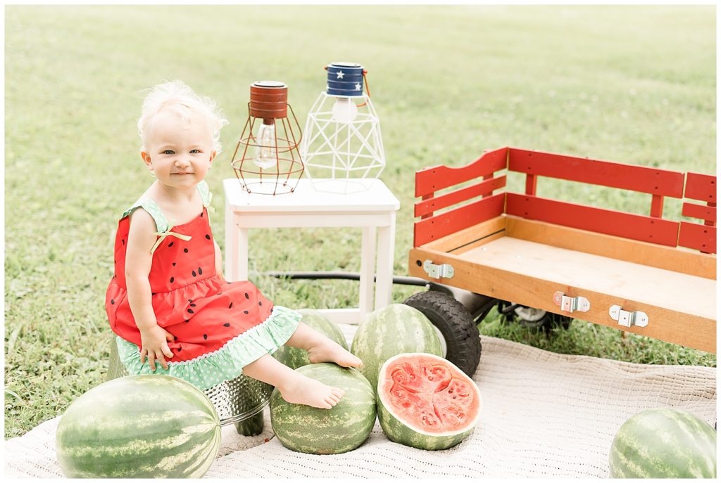 little girl in watermelon dress sitting on bucket