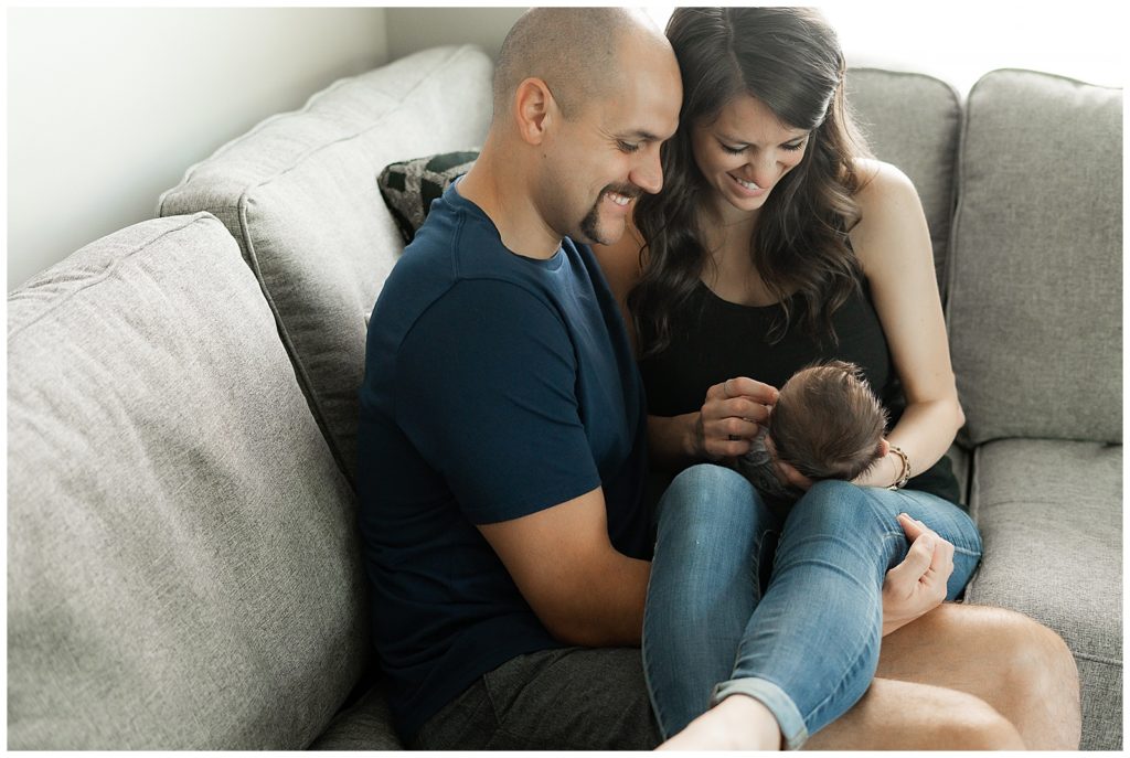 Mother and father holding newborn boy while sitting on couch in Westfield, Indiana